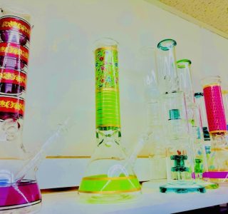 A row of vibrant glass pipes displayed on a shelf, showcasing a variety of colors and designs.
