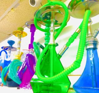 A shelf displaying a variety of colorful hookahs and pipes arranged in a neat row.